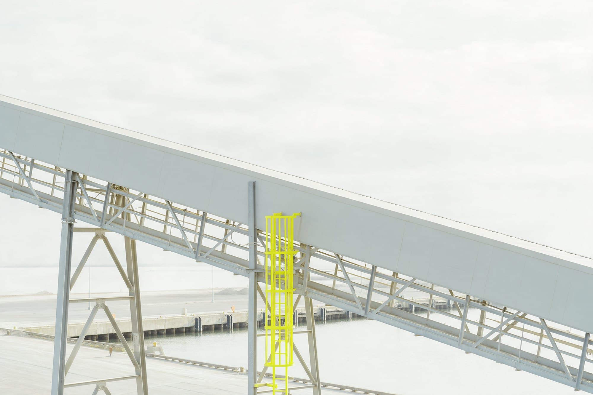 Galeria de correia transportadora de granel atravessando o quadro sobre treliças de aço, com o berço abaixo