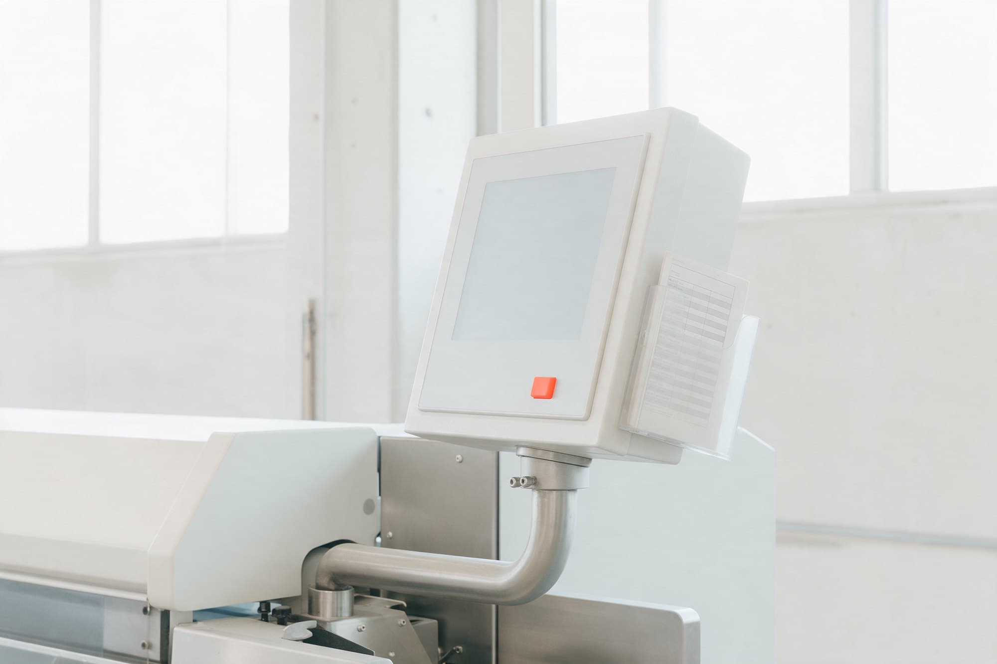 Terminal HMI ao lado de uma máquina, com um cartão de ordem de produção impresso no suporte ao lado