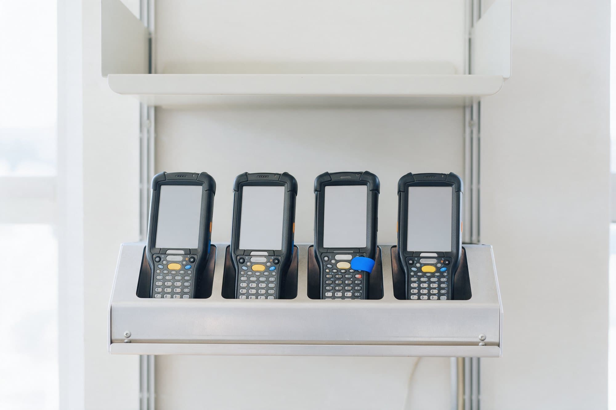 Quatro coletores de dados em um berço de carga na retaguarda de uma loja, com as telas apagadas
