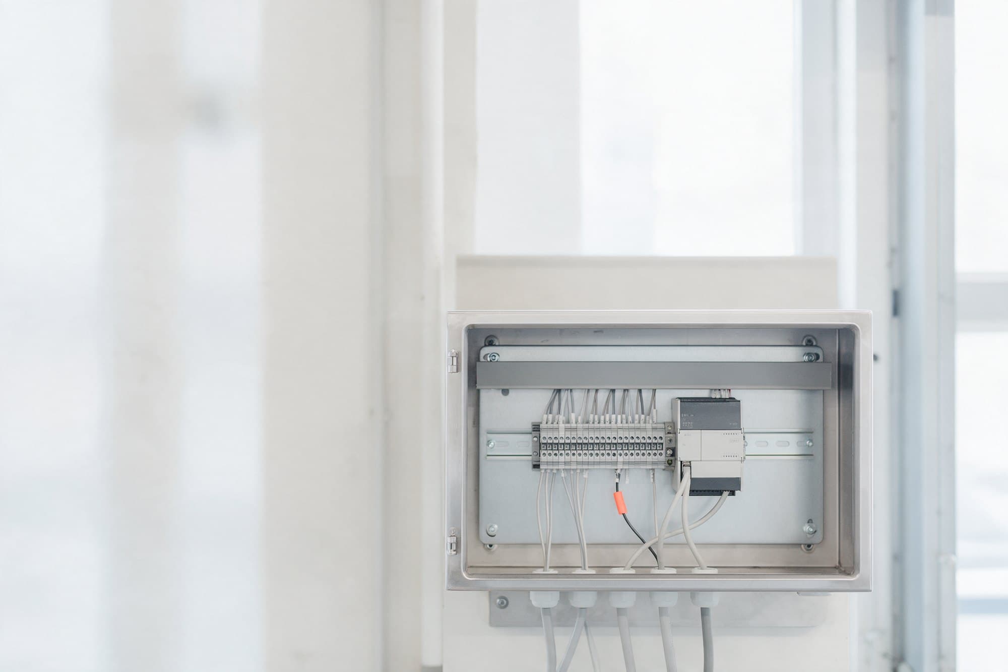 Painel de controle aberto com trilho DIN, blocos de terminais e cabos de sensor entrando por baixo